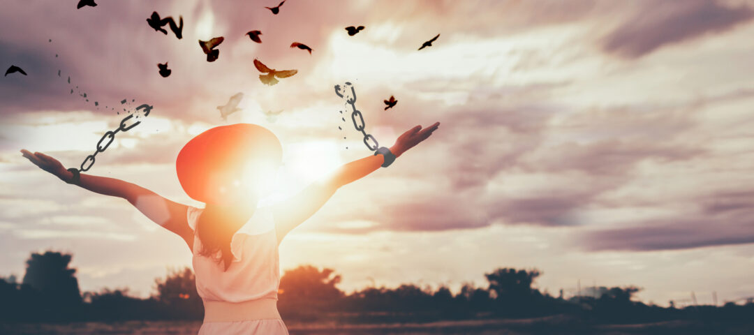 The woman is breaking the chains and setting the birds free, enjoying the nature at sunrise. concept of freedom