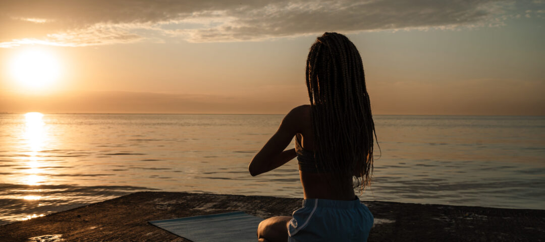 Image of calm african american girl in sportswear meditating on concrete promenade outdoors